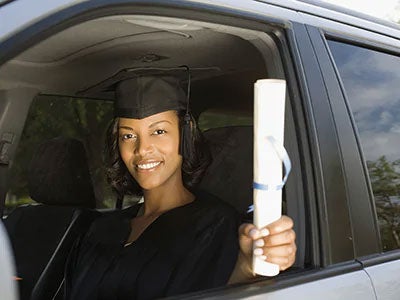 College student holding their diploma out the window of their car