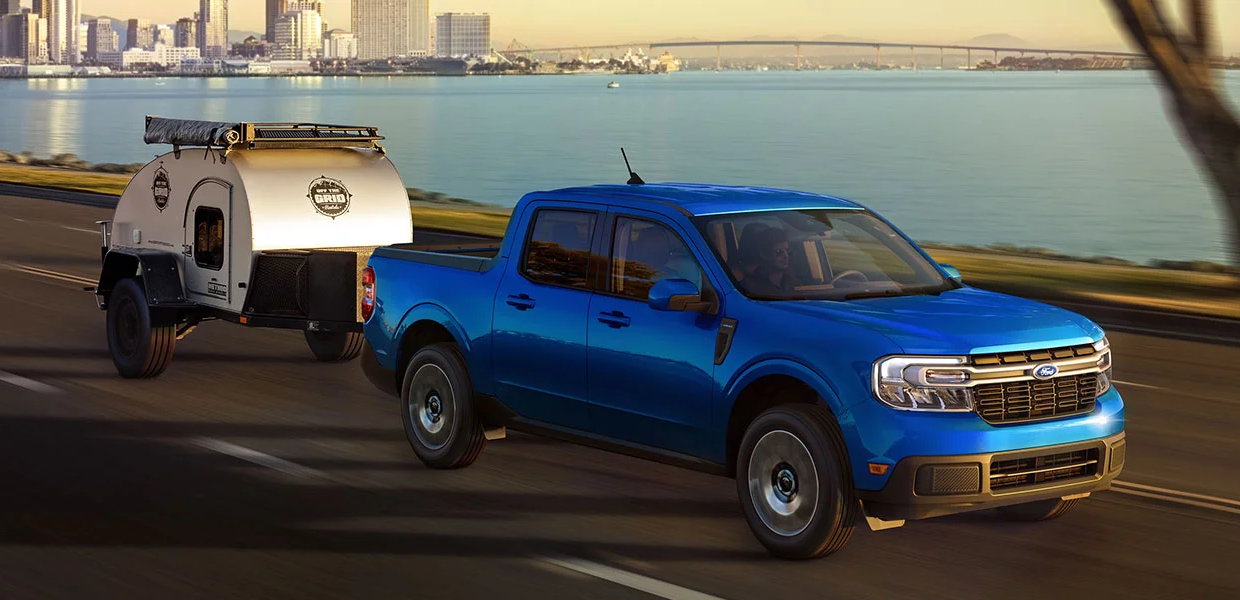 A 2023 Ford Maverick pulling a small camper trailer along the highway
