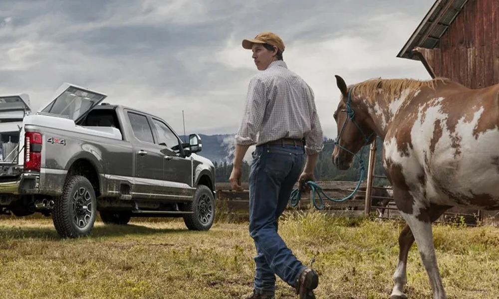 A man leading his horse to a Ford Super Duty pickup truck sitting in a field.