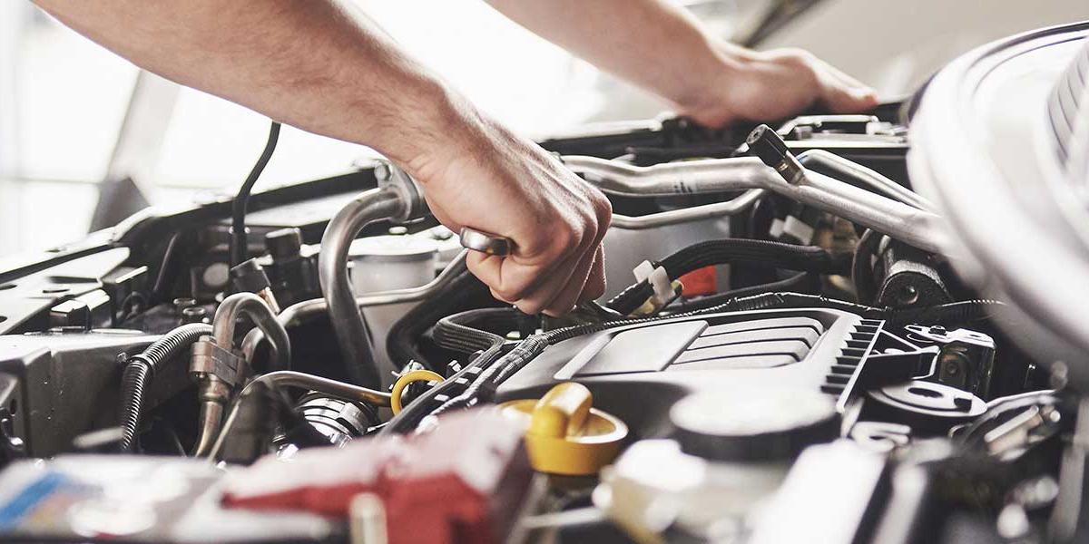 A technician working on a vehicle under the hood