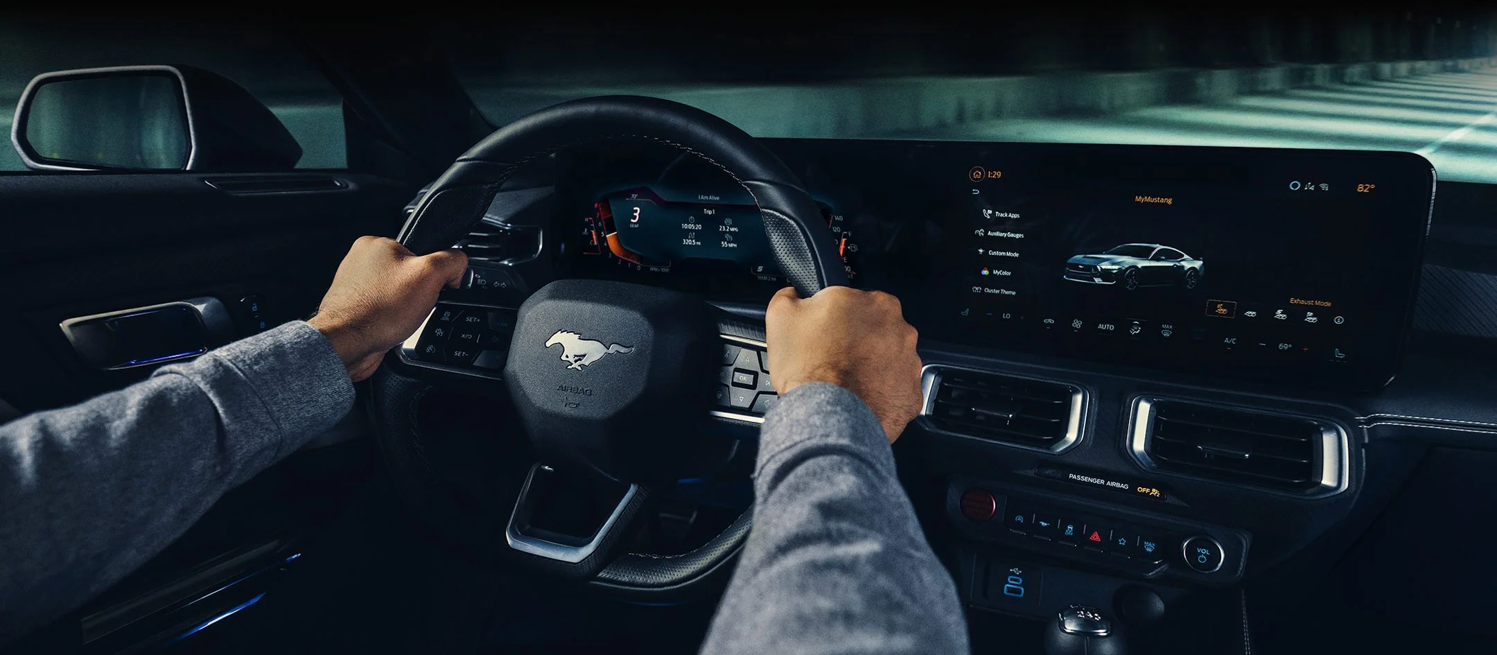 The interior of a 2024 Ford Mustang with a man placing both of his hands on the wheel