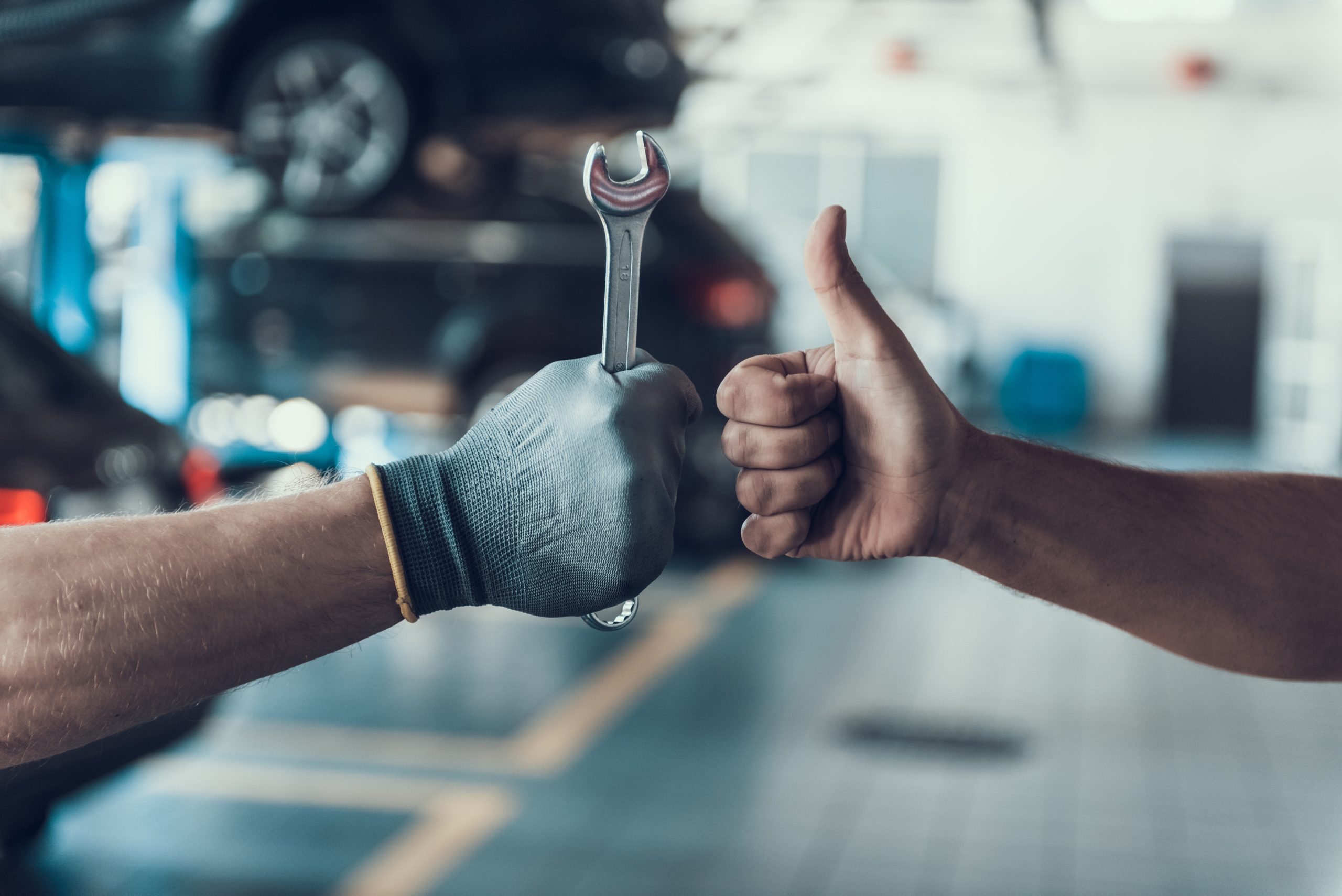 Two mechanics fist-bumping in a thumbs-up pose