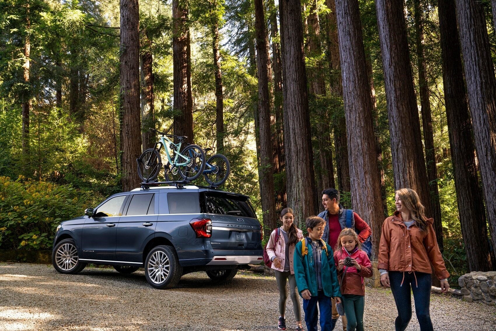 Family in front of Ford with bikes on top of car